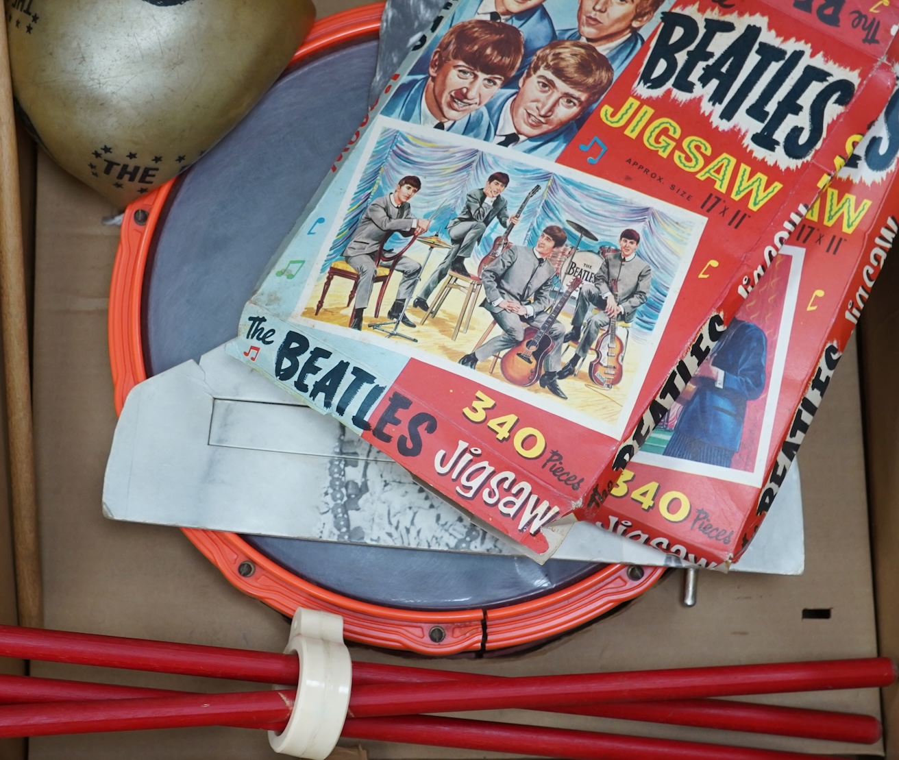 A 1960's Beatles child's plastic drum set in the original card box comprising of a snare drum on a stand, a card cut out bust of Ringo Starr, two 1960s Beatles jigsaws (unchecked) and a Beatles inflatable ball